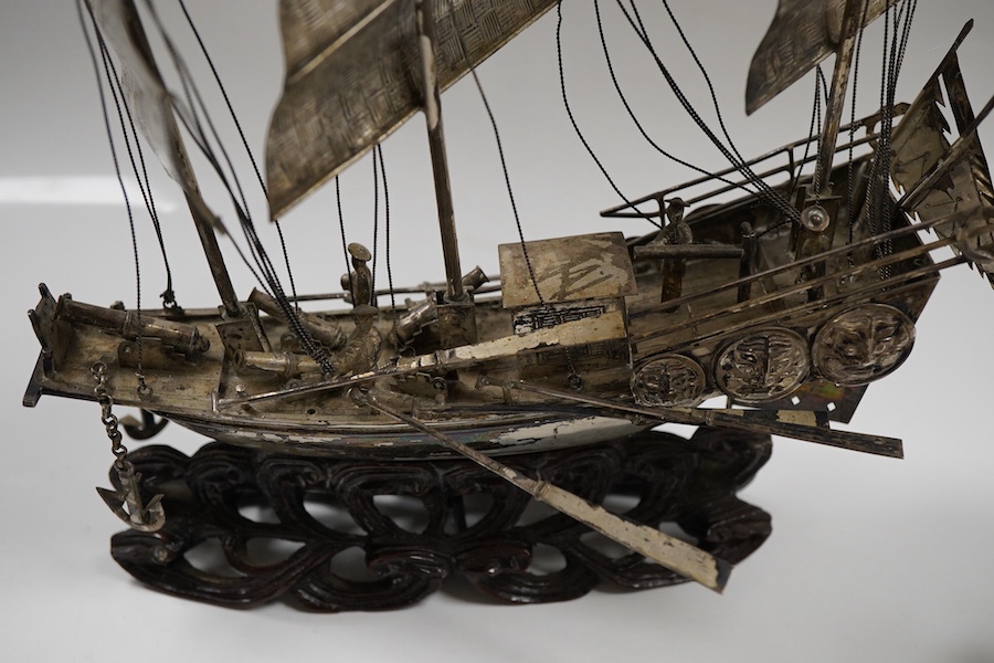 A pair of modern silver fighting cocks, import marks for Sheffield, Assay Office, Sheffield, 1977, height 68mm, together with a Chinese white metal miniature model of a ship, on a carved hardwood base, overall height 20.